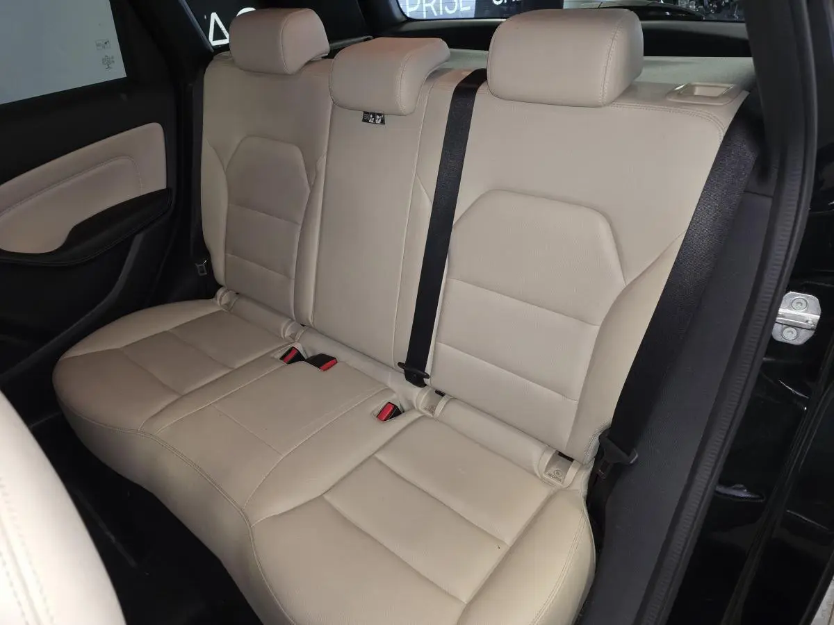 Vue intérieure côté arrière droit montrant la banquette beige clair en similicuir de la Mercedes Classe B noire.