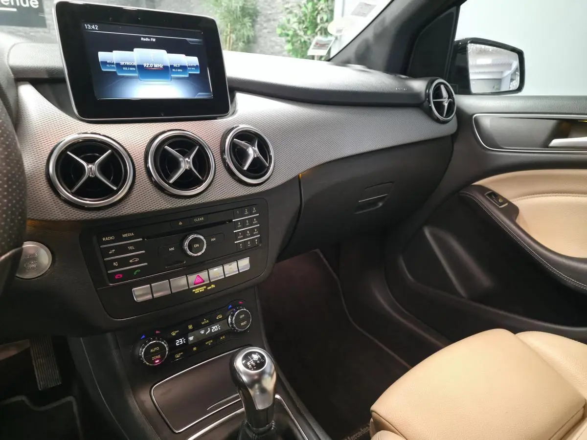 Intérieur avant droit de la Mercedes Classe B 180 d noir, tableau de bord avec écran central et levier de vitesses manuel.