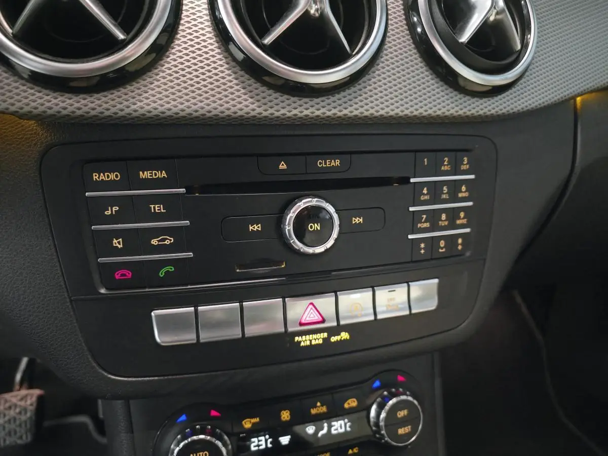 Vue rapprochée de la console centrale noire de la Mercedes Classe B 180 d Intuition avec commandes multimédia et climatisation digitale.