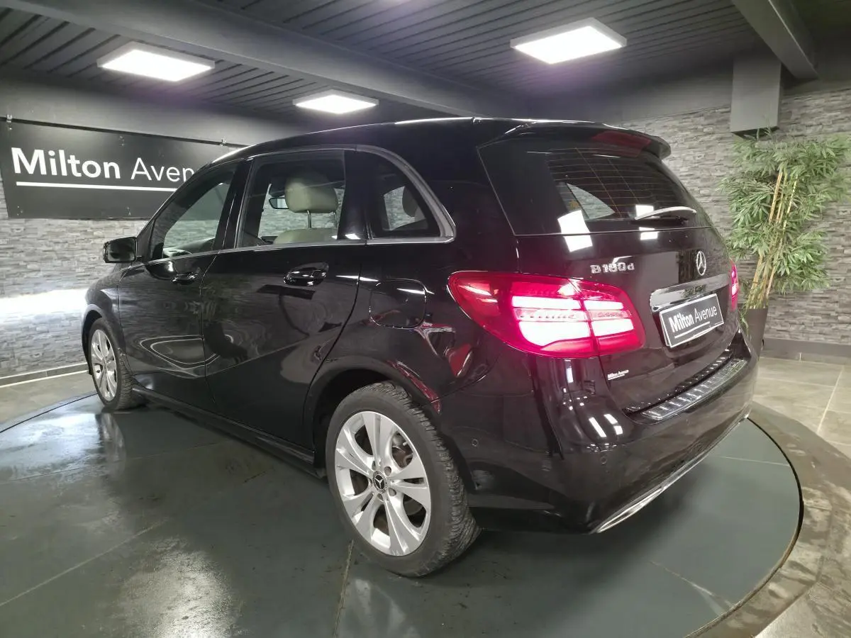 Mercedes Classe B 180d noir vue 3/4 arrière droit, feux arrière allumés et jantes alliage 17 pouces.