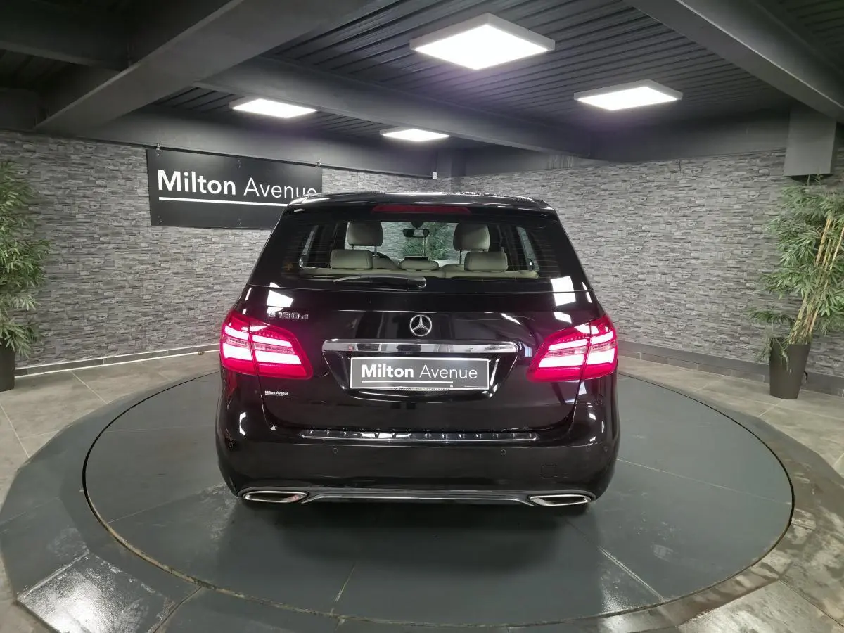 Vue arrière d'une Mercedes Classe B 180 d Intuition noire, feux LED allumés, double sortie d'échappement visible.