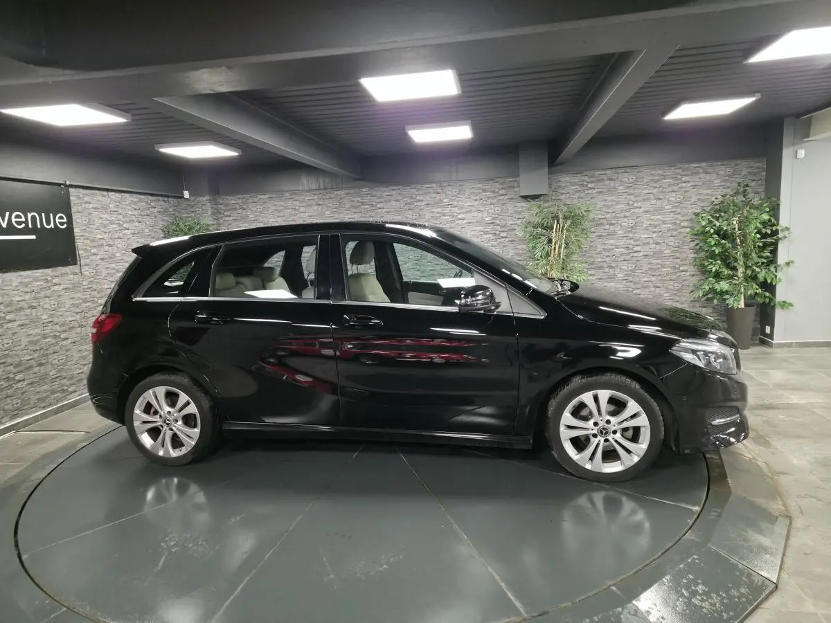 Vue latérale gauche d'une Mercedes Classe B noire 2018 avec jantes alliage 17 pouces dans un showroom.