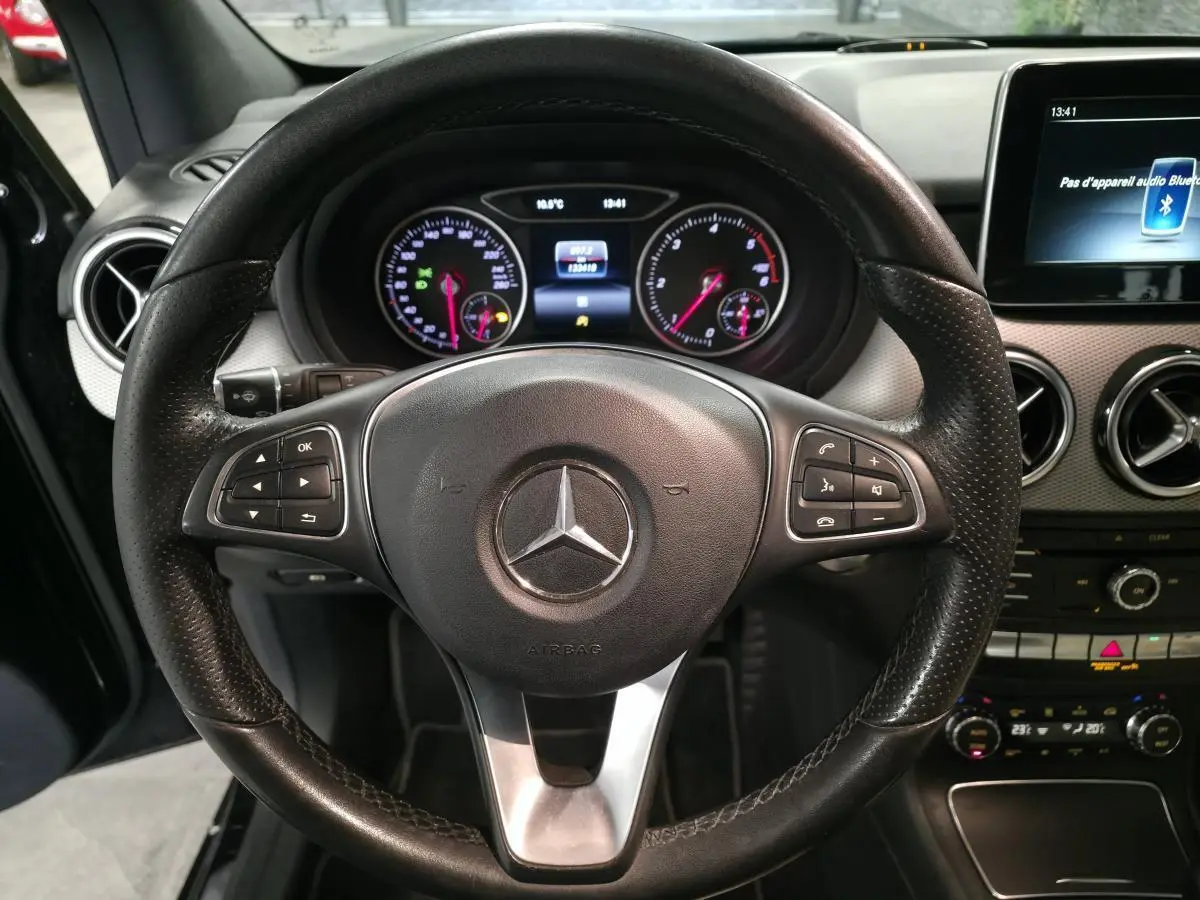 Vue rapprochée du volant cuir noir multifonctions et du tableau de bord digital d’une Mercedes Classe B 180 d 2018.