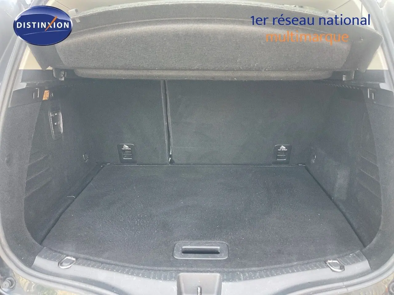Coffre ouvert d’un Renault Scénic IV noir, montrant un espace de chargement propre et spacieux.