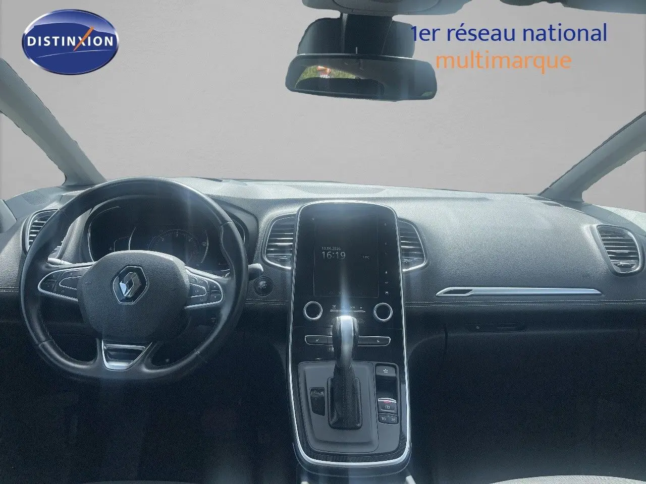 Vue intérieure frontale du tableau de bord noir du Renault Scenic IV avec écran tactile vertical et volant multifonction.