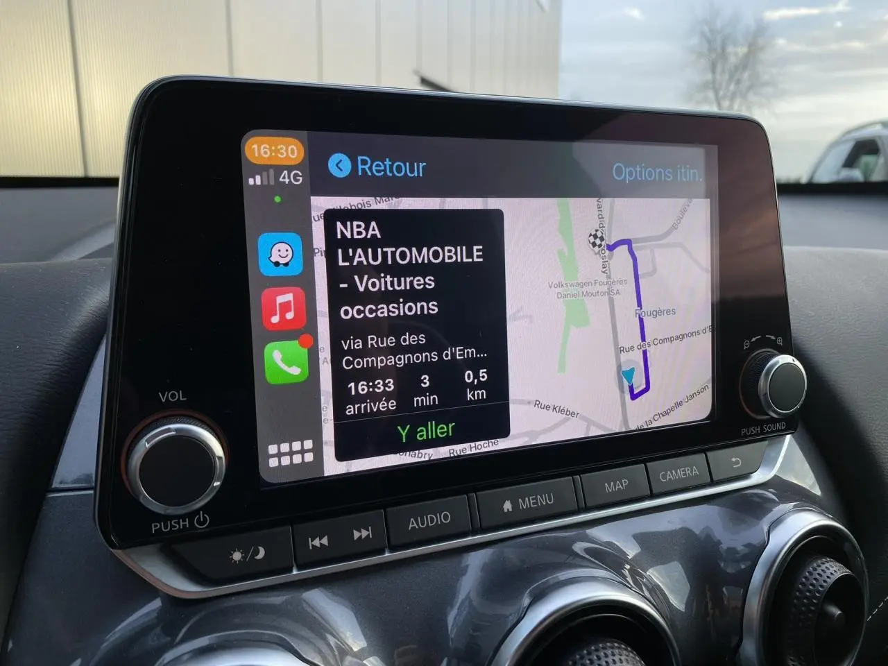 Écran tactile GPS du Nissan Juke blanc perle 2024, vue intérieure du tableau de bord avec commandes audio.