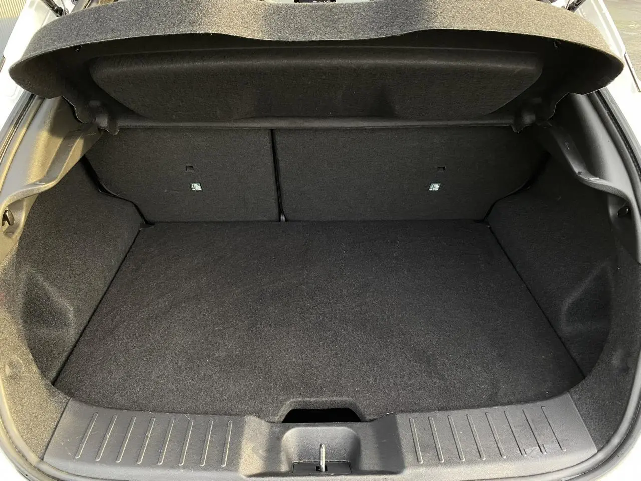 Coffre ouvert en vue arrière d'une Nissan Juke blanc perle 2024, montrant un espace de chargement propre et spacieux.