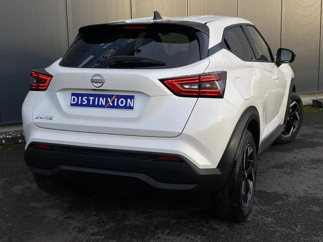 Vue 3/4 arrière droite du Nissan Juke blanc perle avec feux arrière LED et jantes alliage noires.