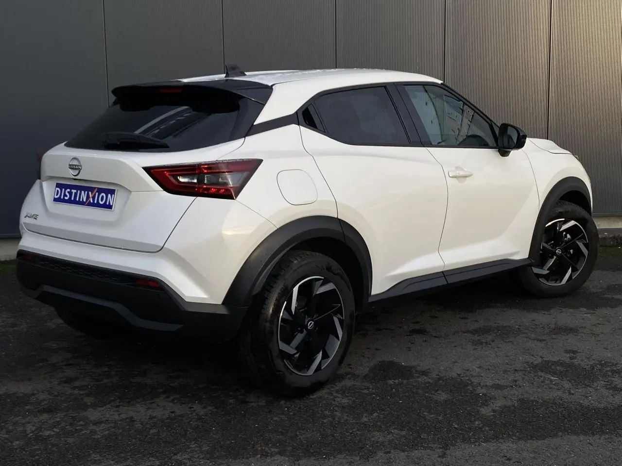 Nissan Juke blanc perle en 3/4 arrière droit, avec jantes alliage noires et toit noir contrasté.
