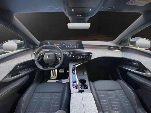 Vue intérieure avant du Peugeot 5008 2025, tableau de bord moderne avec écran tactile panoramique et sièges gris-noir.