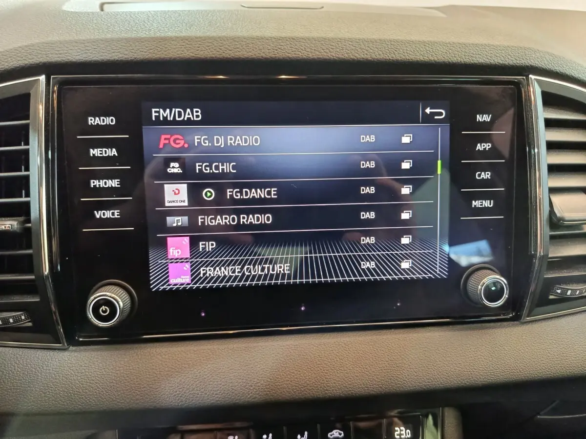 Écran tactile central de la Skoda Karoq blanc 2024 affichant les stations radio FM/DAB, vue de face intérieure.