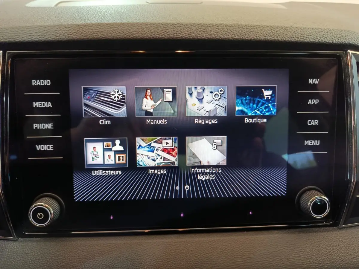Écran tactile central du Skoda Karoq blanc 2024 affichant le menu principal avec options clim, réglages et navigation.