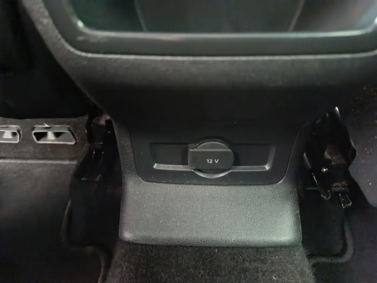 Prise 12V noire vue de face dans l'habitacle du Skoda Karoq blanc, version 2024, côté arrière central.