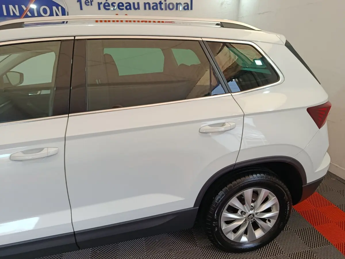 Vue latérale côté droit d'un Skoda Karoq blanc 2024 avec jante alliage et vitres teintées.