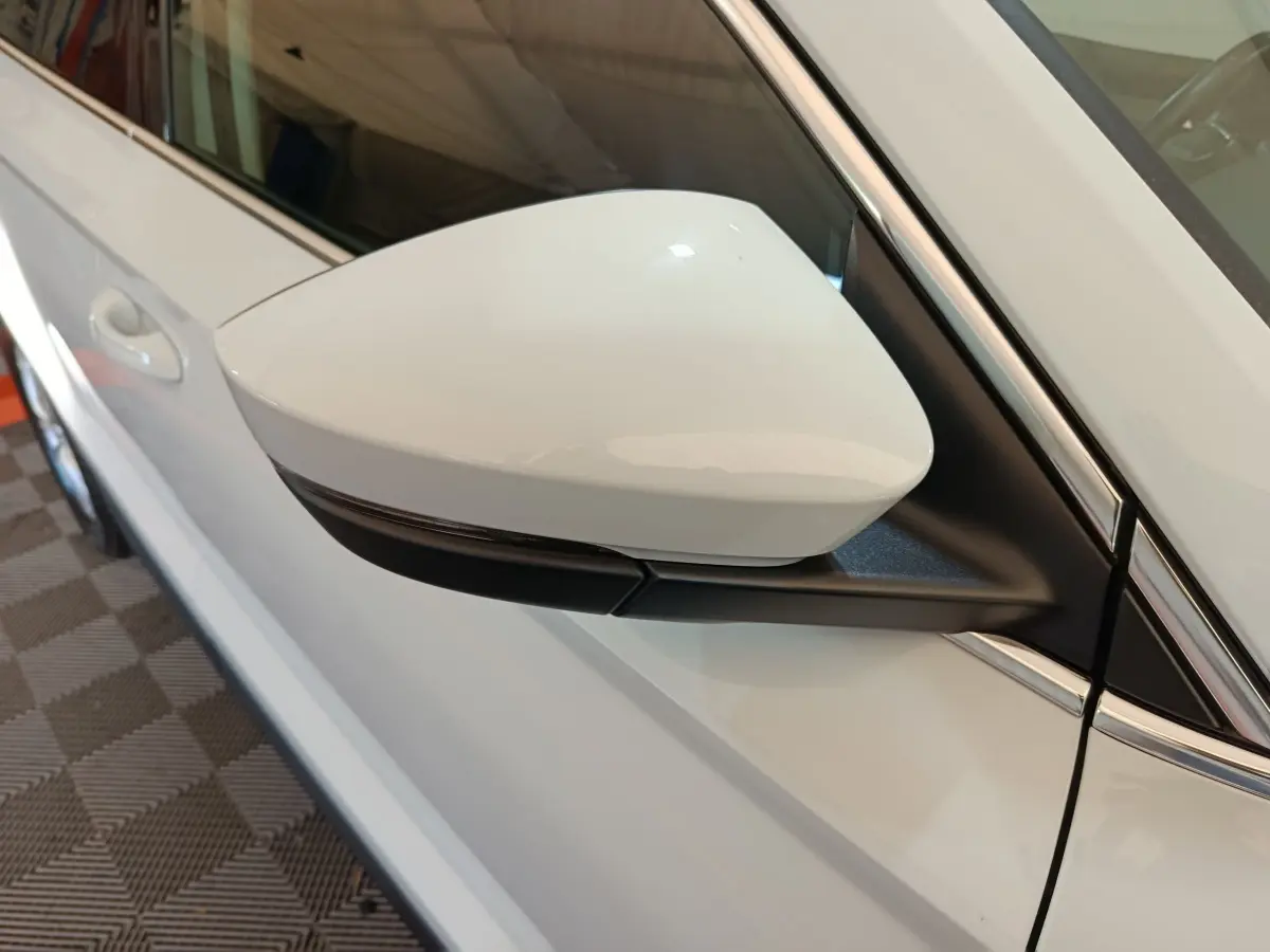 Gros plan sur le rétroviseur droit blanc du Skoda Karoq 2024, avec carrosserie blanche visible en arrière-plan.