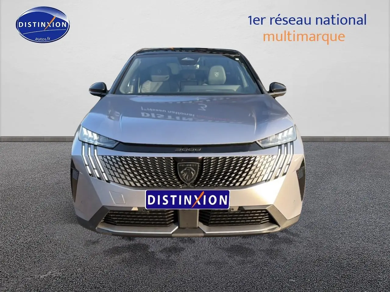 Vue frontale d’un Peugeot 3008 gris 2025 avec calandre distinctive et phares LED verticaux allumés.