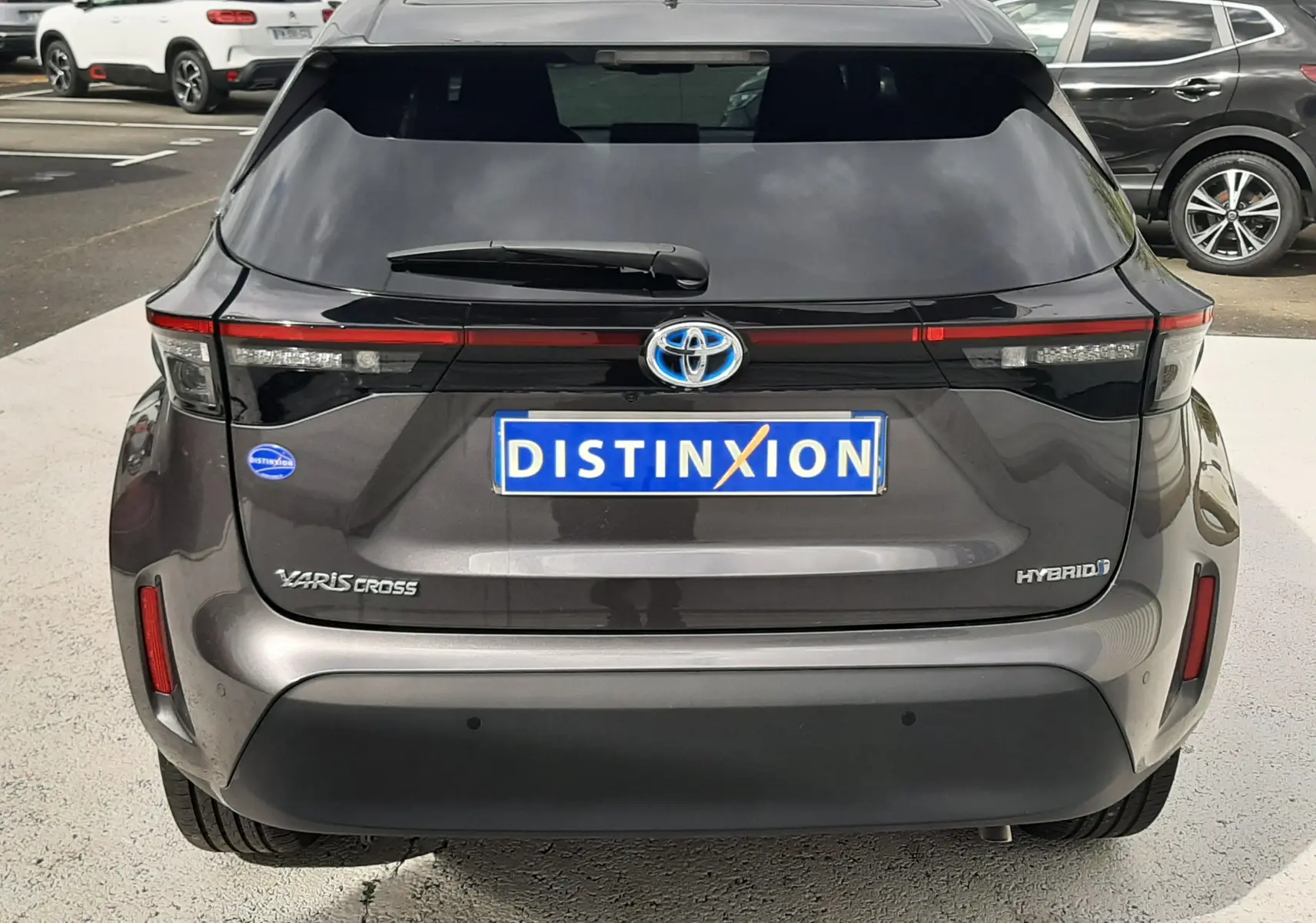 Vue arrière d'une Toyota Yaris Cross 1.5 Hybride gris atlas métal, avec feux LED et logo hybride bien visibles.