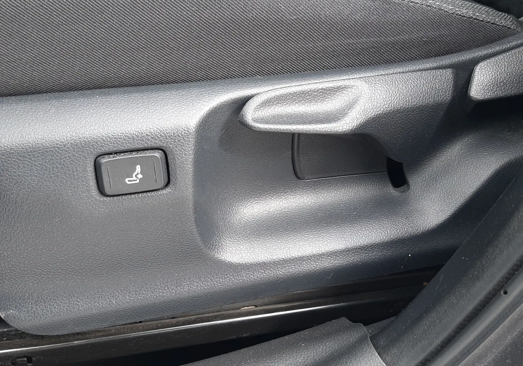 Détail du réglage manuel et bouton de siège chauffant sur le côté gauche d’un siège tissu gris dans une Toyota Yaris Cross 2024.