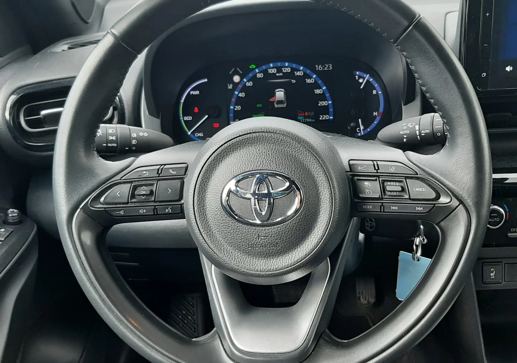 Vue intérieure centrée sur le volant noir de la Toyota Yaris Cross 2024 avec tableau de bord digital et commandes au volant.