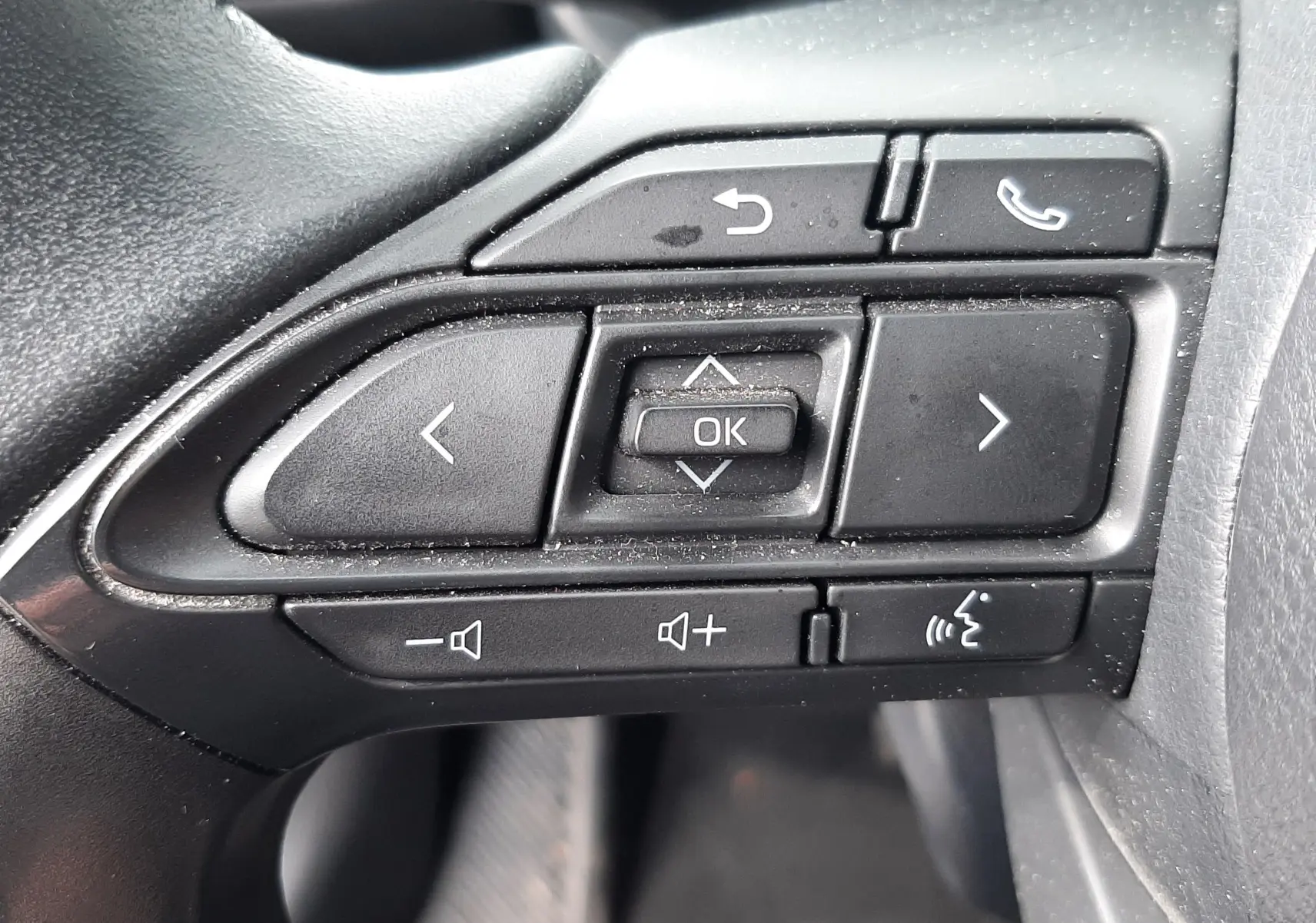 Gros plan sur les commandes multifonctions au volant noir de la Toyota Yaris Cross 2024, version hybride gris atlas metal.