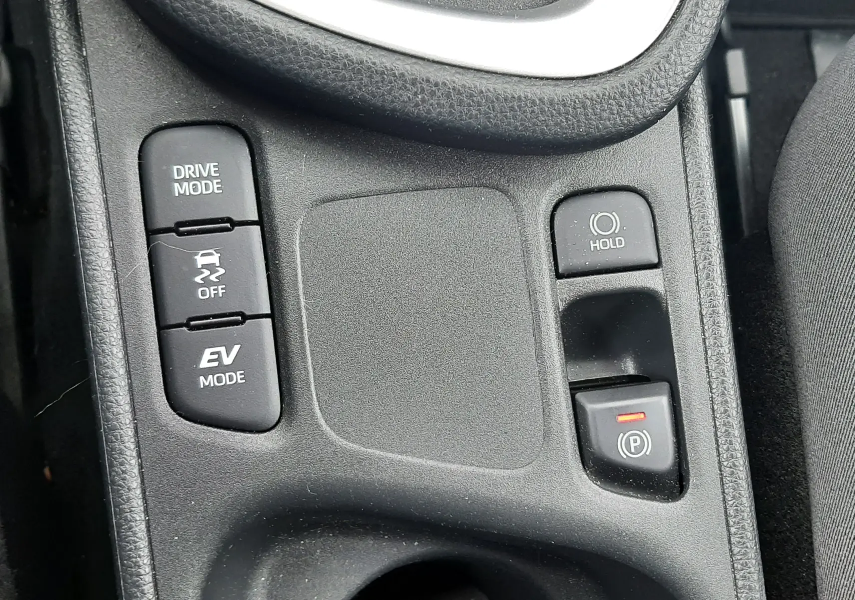 Vue rapprochée de la console centrale grise de la Toyota Yaris Cross 2024, avec boutons Drive Mode et frein électrique.