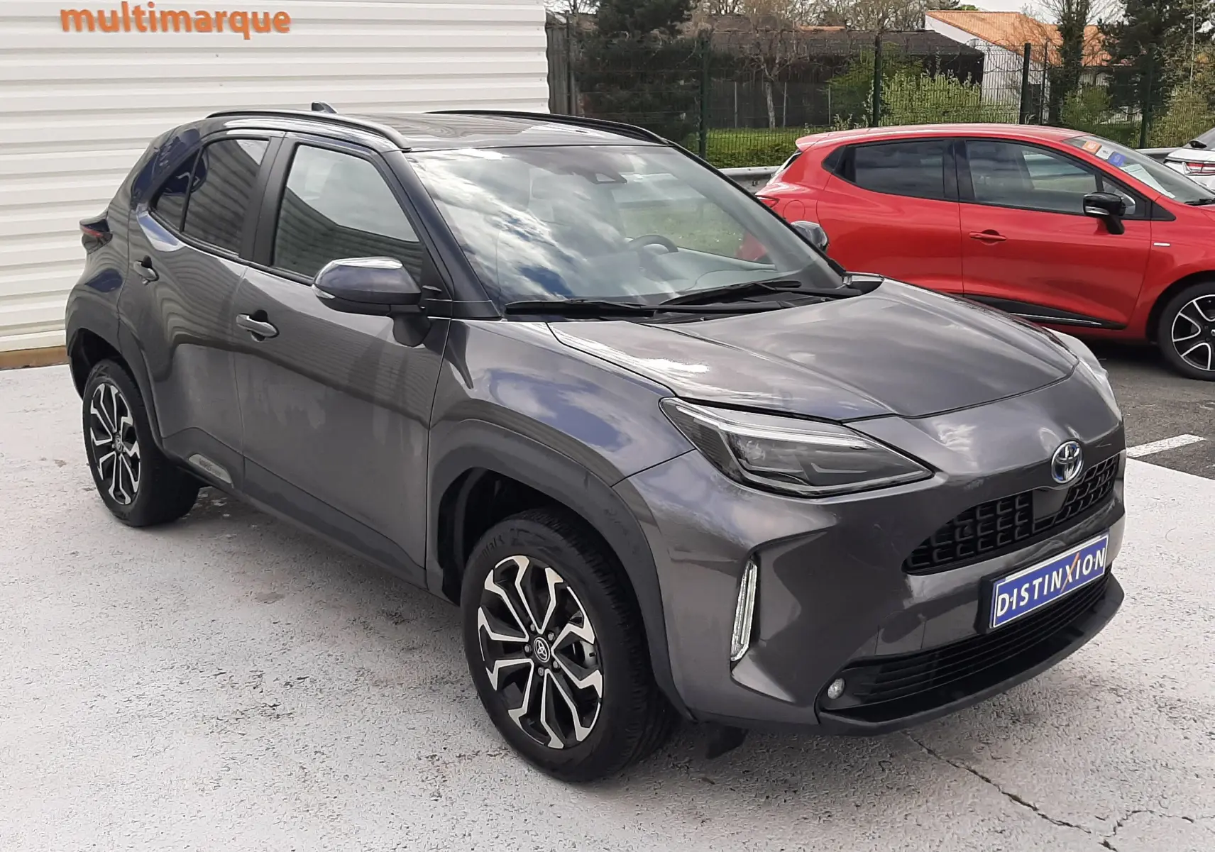 Toyota Yaris Cross gris atlas métal vue 3/4 avant droit avec jantes bi-ton et toit noir brillant.