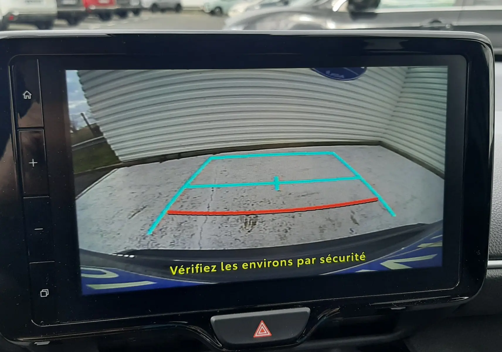 Écran de caméra de recul dans une Toyota Yaris Cross 2024, affichant les lignes de guidage en bleu et rouge.