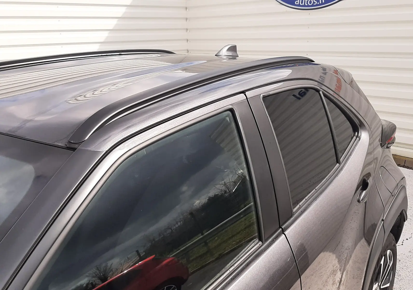 Vue rapprochée côté droit arrière du Toyota Yaris Cross 2024 gris atlas métal avec toit noir et barres de toit.