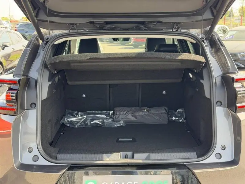 Coffre ouvert vu de l'arrière d'un Citroën C5 Aircross gris Platinium avec banquette arrière et cache-bagages visibles.