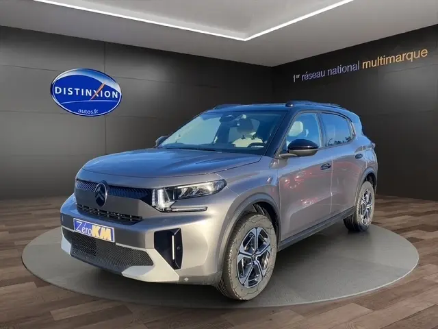 Vue 3/4 avant d'un Citroën C3 Hybrid 145 E-DCS6 MAX gris foncé avec jantes distinctives en concession.