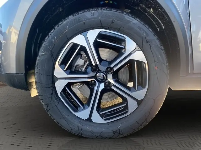 Gros plan sur la roue avant droite d’une Citroën C3 Hybrid 145 E-DCS6 MAX gris foncé avec jante alliage bicolore.