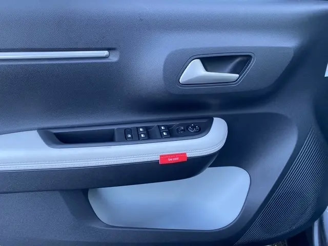 Gros plan sur la porte intérieure côté conducteur de la Citroën C3 Hybrid 145 gris foncé, avec commande des vitres et étiquette "be cool".