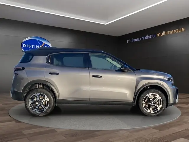 Vue latérale droite d'un Citroën C3 gris foncé 2026 en hybride, avec jantes distinctives et toit noir contrasté.