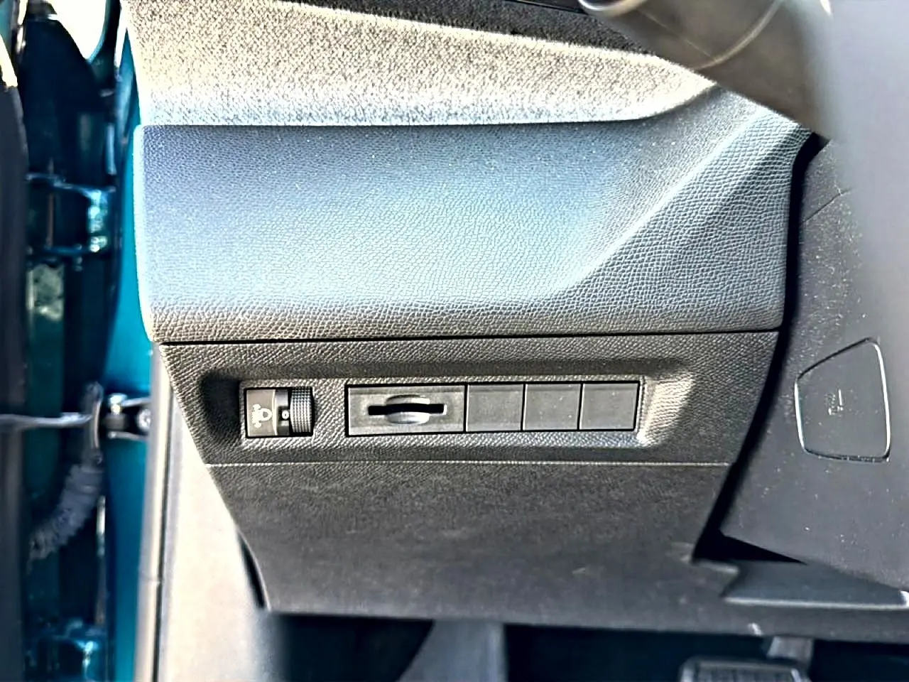 Vue rapprochée du panneau de commandes latéral gauche intérieur de la Peugeot 408 bleu, avec réglage éclairage et emplacements vides.
