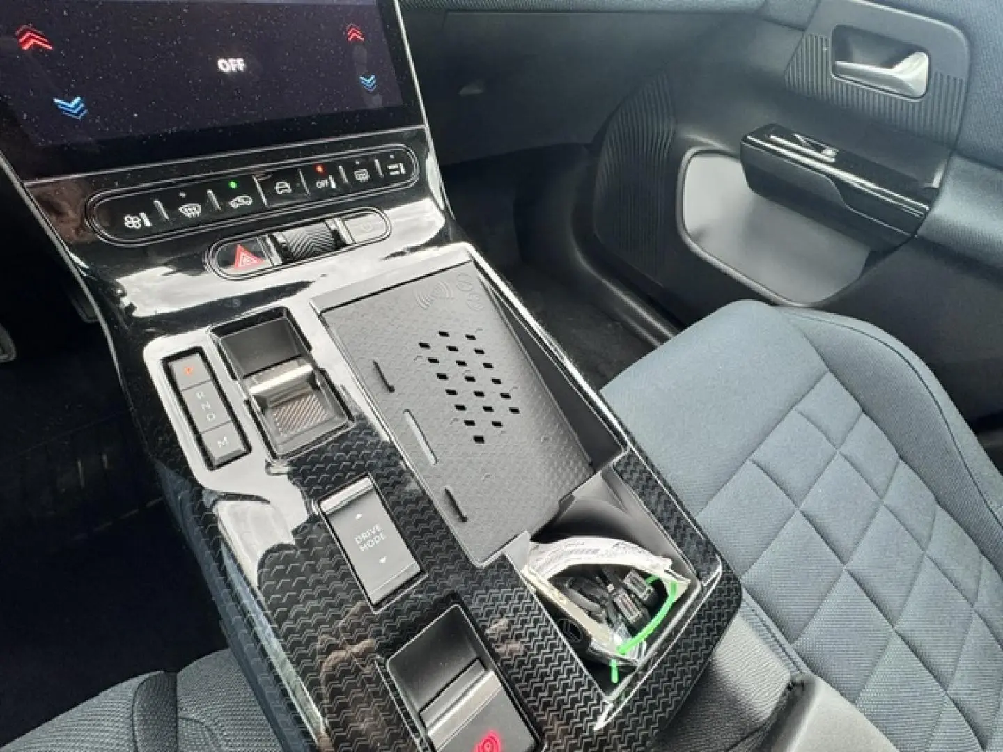 Vue rapprochée de la console centrale noire brillante et du siège passager tissu bleu dans un Citroën C5 Aircross 2026.