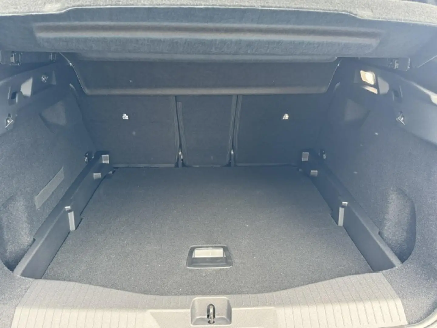 Coffre ouvert en vue arrière d'un Citroën C5 Aircross gris Platinium, espace de chargement spacieux et tapis noir.