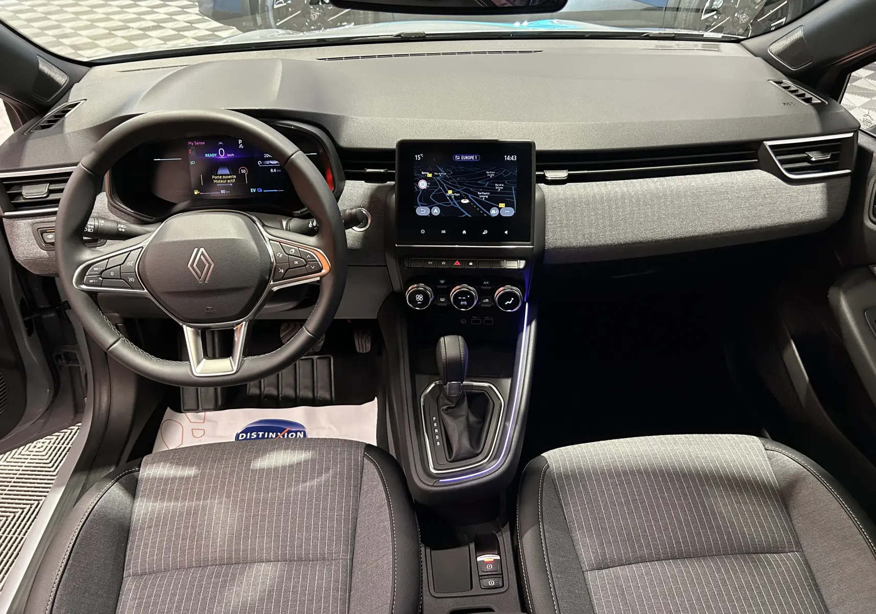 Vue intérieure avant de la Renault Clio V E-Tech gris Rafale, tableau de bord avec écran tactile et volant multifonction.