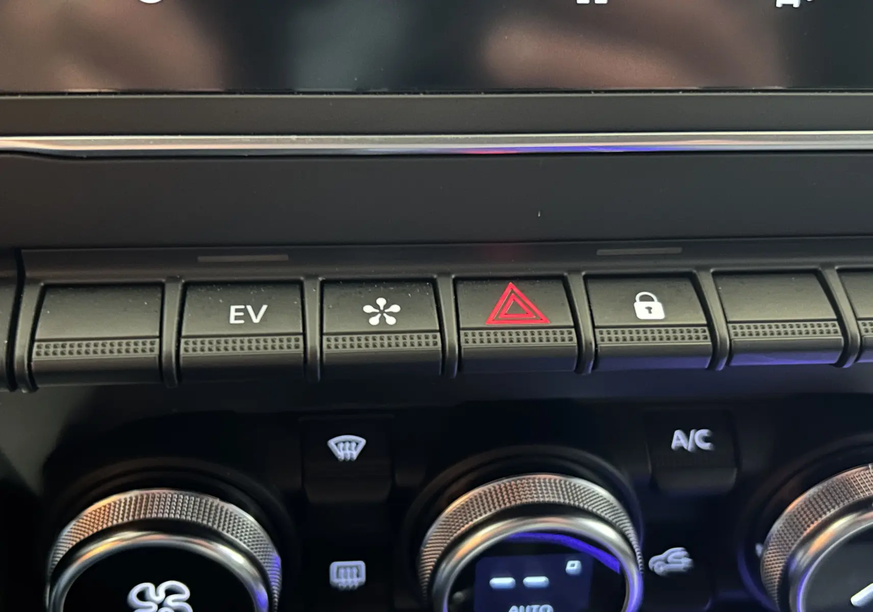 Gros plan sur la console centrale de la Renault Clio V hybride, montrant les boutons de contrôle et les molettes argentées.