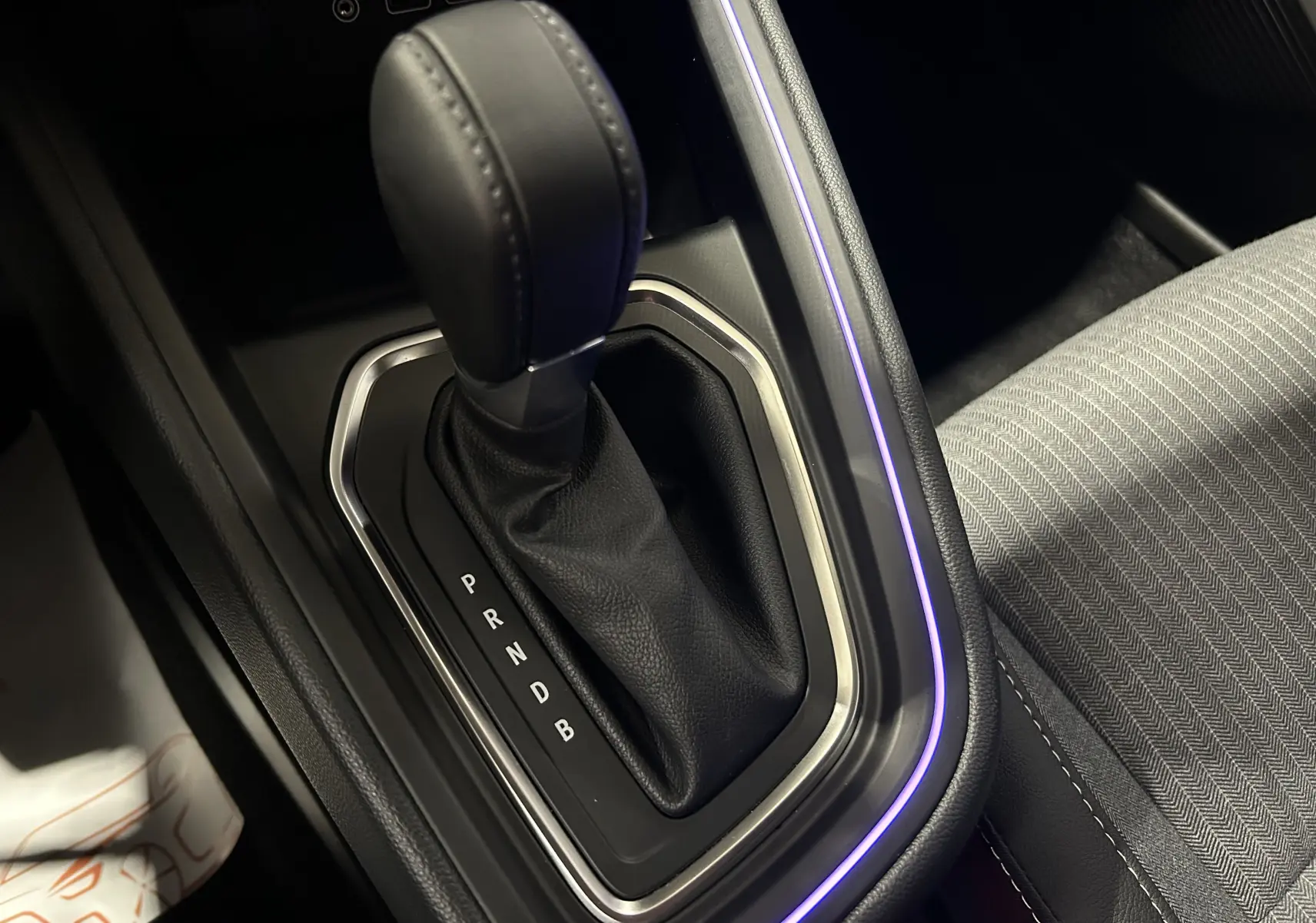 Gros plan sur la commande de boîte automatique noire avec éclairage d'ambiance violet dans l'habitacle d'une Renault Clio V gris rafale.