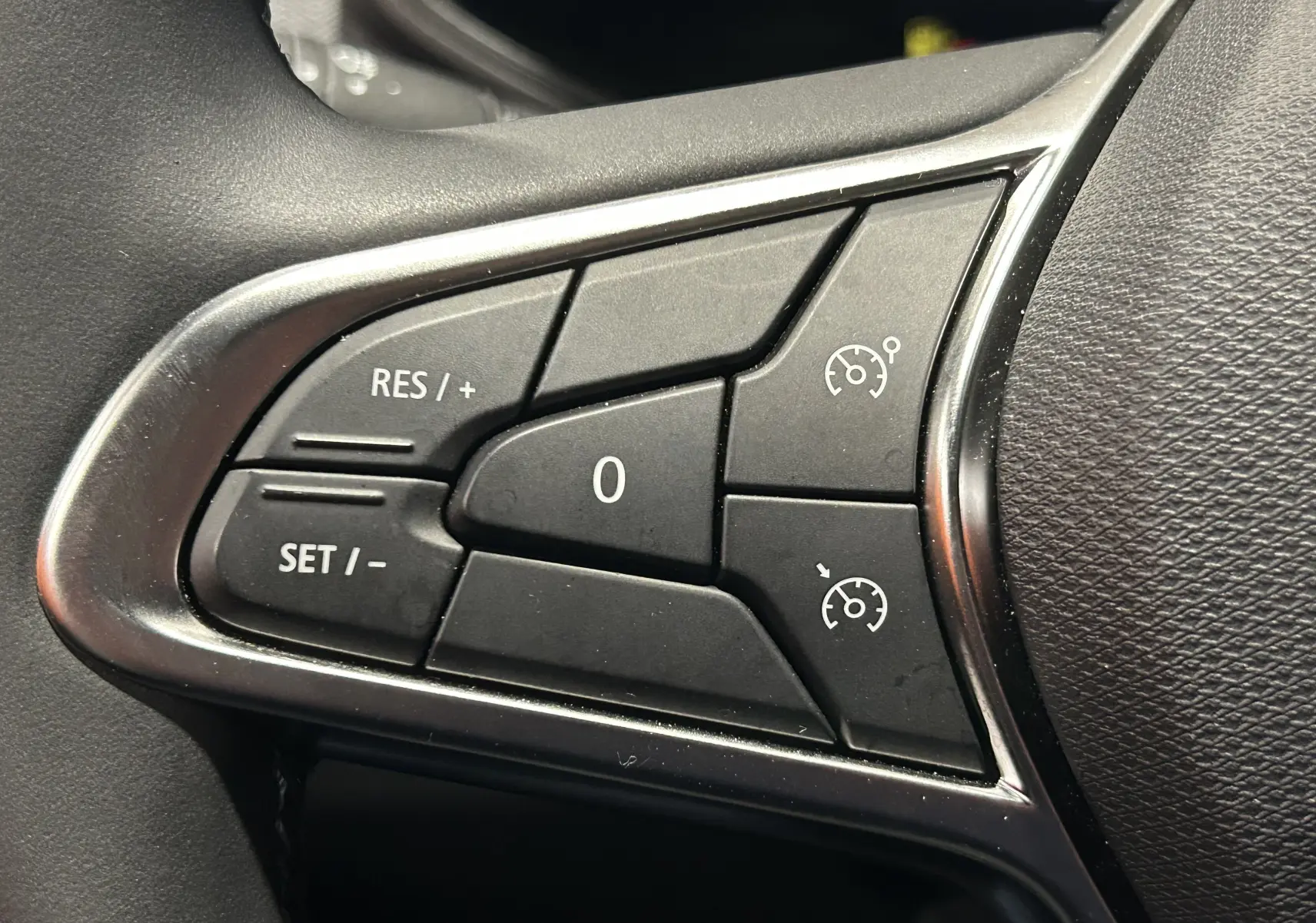 Gros plan sur les commandes de régulateur de vitesse au volant d’une Renault Clio V gris Rafale, côté gauche.