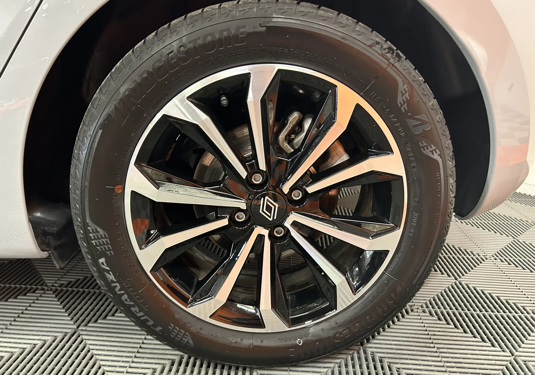 Gros plan sur la roue avant droite d'une Renault Clio V gris Rafale, jante alliage bicolore et pneu Bridgestone.