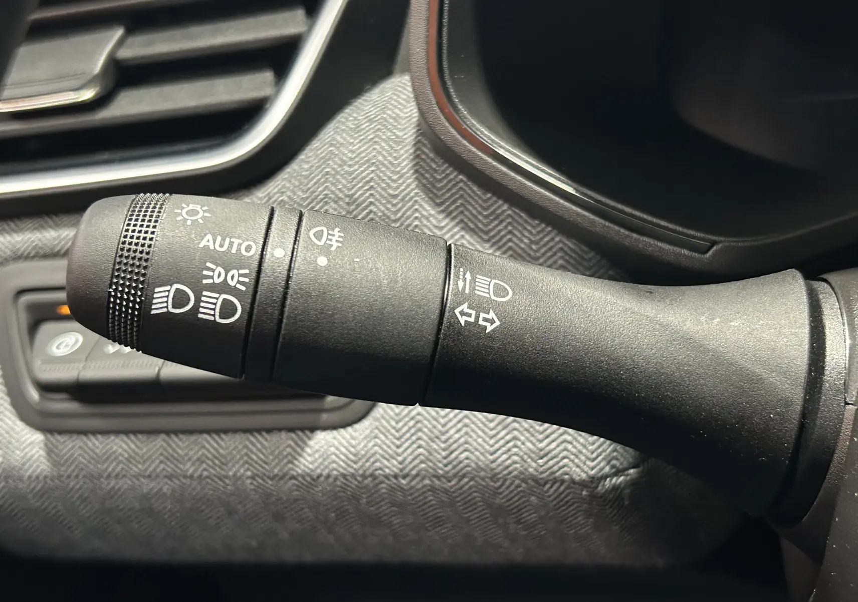 Gros plan sur la commande des feux et clignotants dans l’habitacle gris noir de la Renault Clio V E-Tech Hybrid.