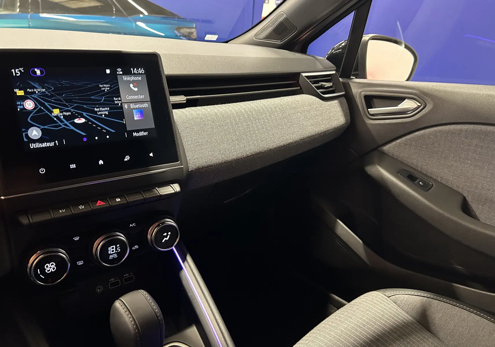 Vue intérieure côté passager de la Renault Clio V E-Tech gris Rafale, avec écran tactile et console centrale moderne.