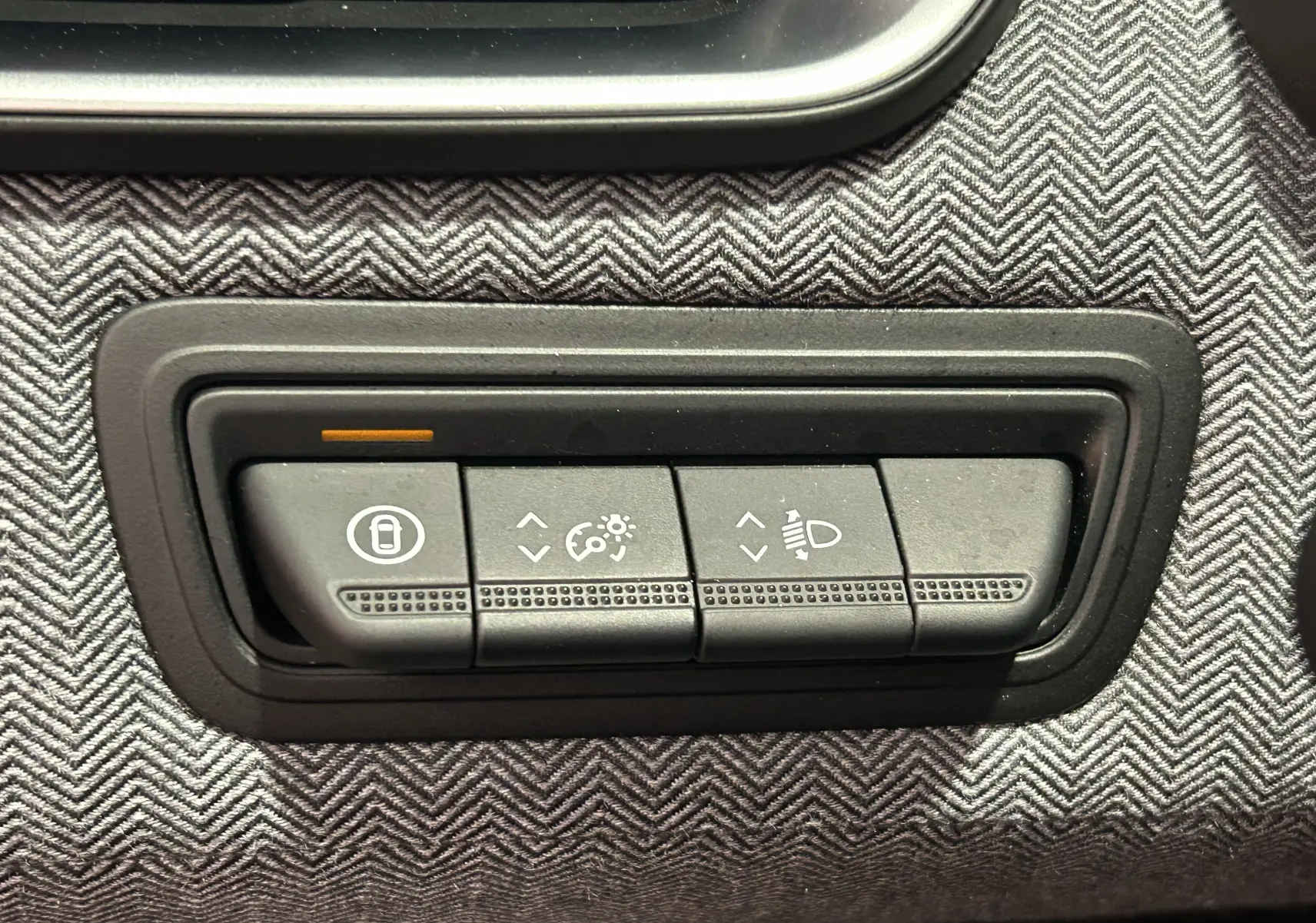 Gros plan sur les boutons de réglage d’éclairage et verrouillage dans l’habitacle gris à motif chevrons d’une Renault Clio V.