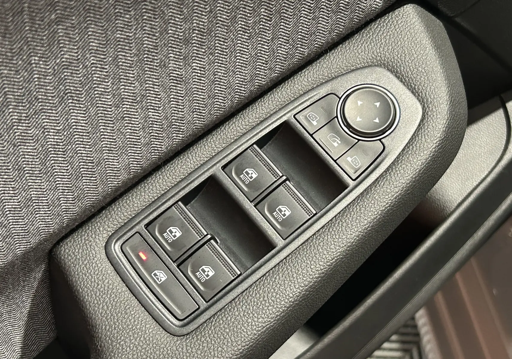 Gros plan sur les commandes des vitres électriques et rétroviseurs sur la porte côté conducteur d'une Renault Clio V gris Rafale.