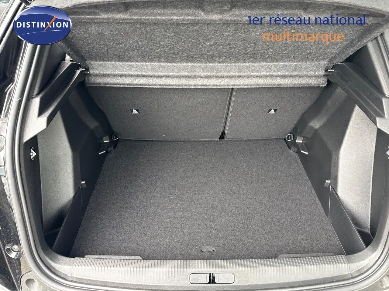 Coffre ouvert du Peugeot 2008 Hybrid noir métal, montrant l'espace de chargement vide et la finition intérieure sombre.