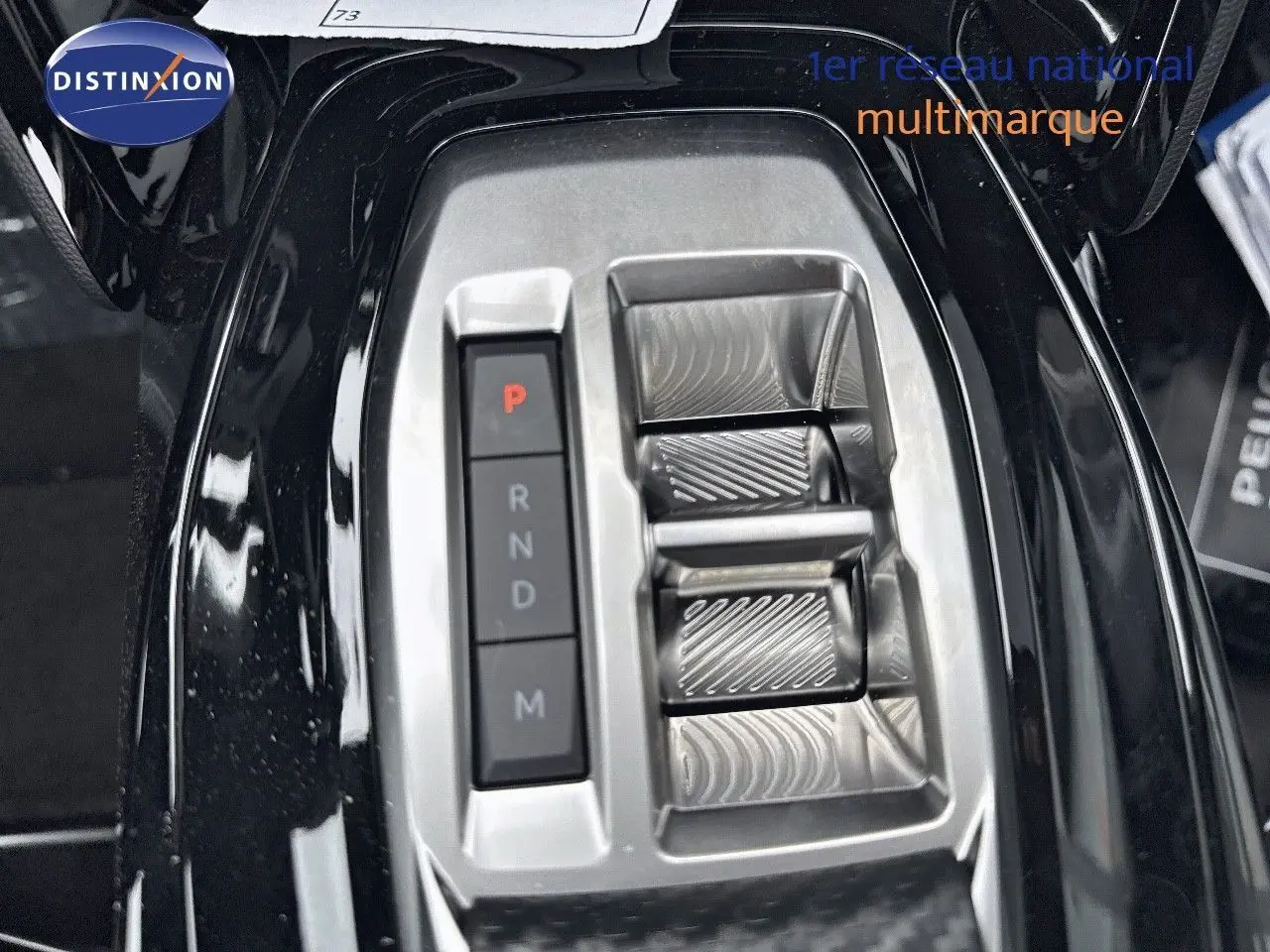 Gros plan sur la console centrale noire métal du Peugeot 2008 Hybrid 136ch avec commandes de boîte automatique et levier design.
