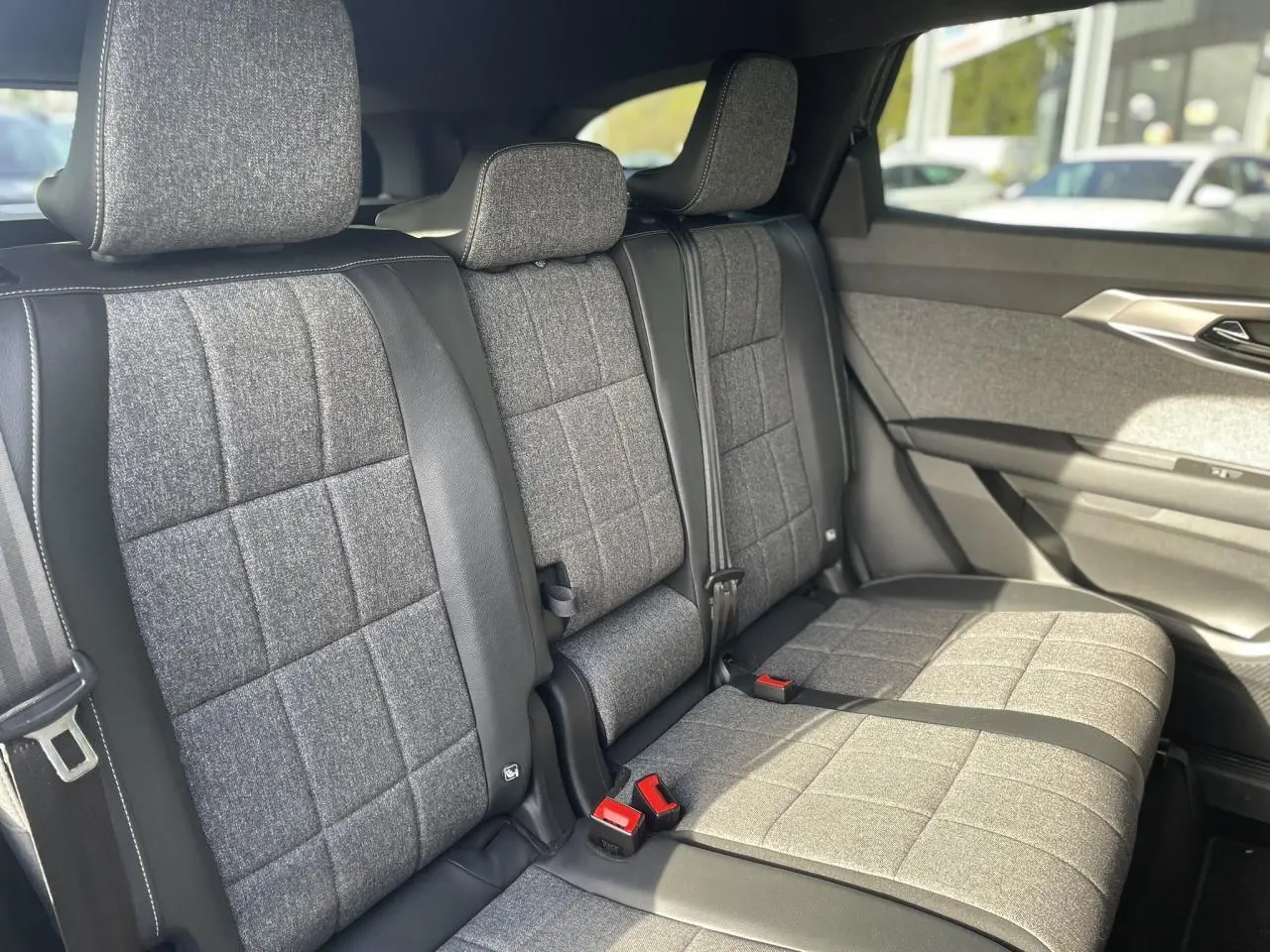 Vue latérale intérieure montrant la banquette arrière en tissu gris avec surpiqûres blanches du Renault Espace 2024.