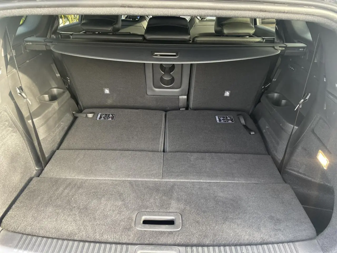 Vue du coffre arrière du Renault Espace noir étoilé 2024 avec sièges rabattus et cache-bagages déployé.