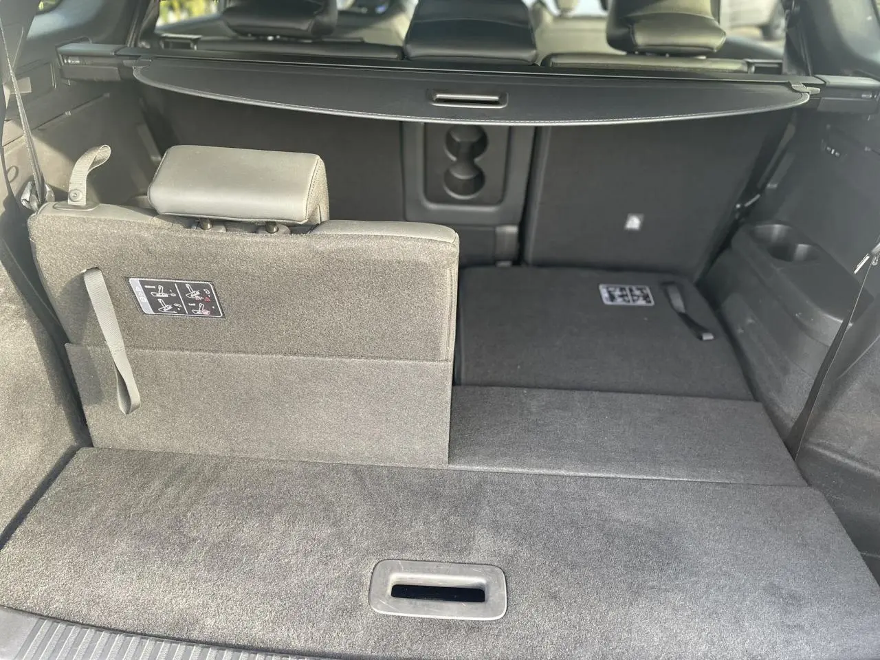Vue intérieure du coffre du Renault Espace noir étoilé 2024, siège arrière partiellement rabattu côté gauche.